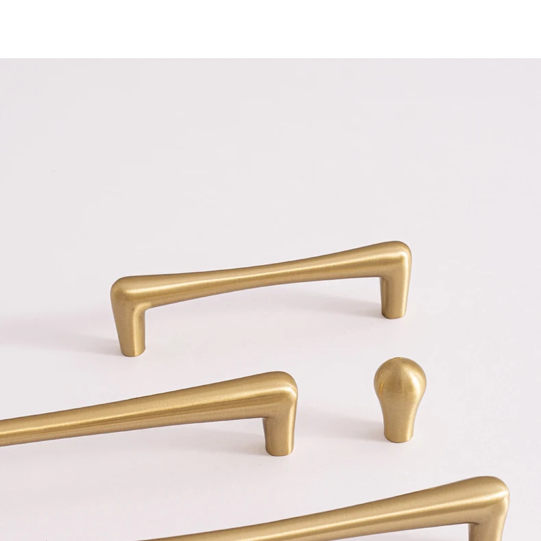 Brass bar pulls and teardrop knob on a light surface