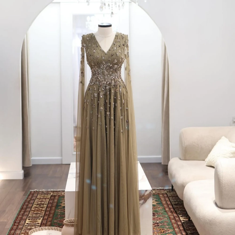 Vestido de tul fluido hasta el suelo, verde oliva empolvado, con cuello en V profundo, manga larga de malla transparente, corpiño fruncido con cuentas de cristal en degradado y estilo modesto.