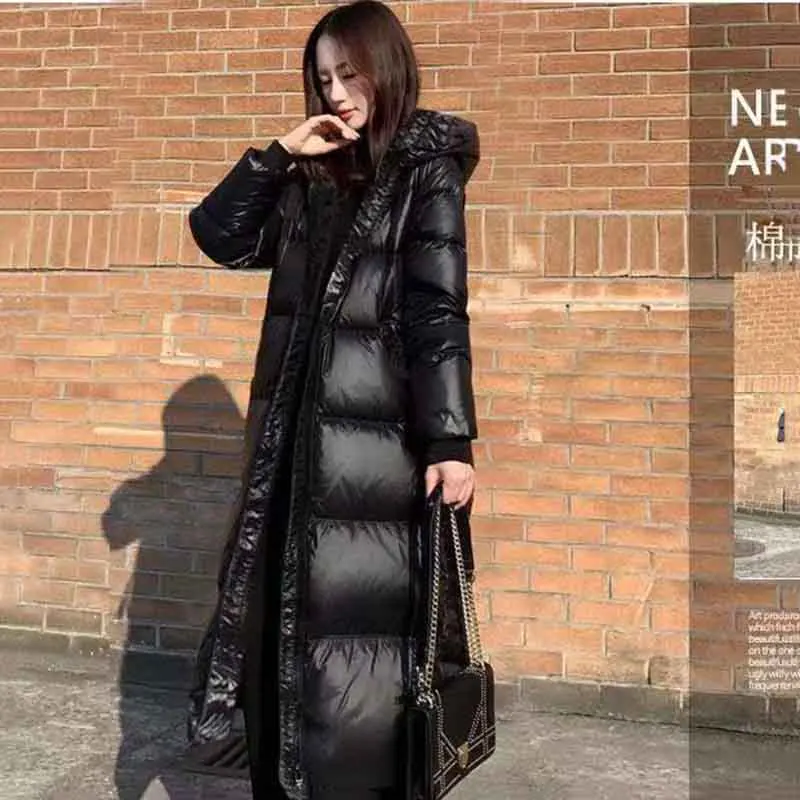 Chaqueta acolchada cálida de plumón negro para mujer, abrigo largo hasta la rodilla, abrigo de algodón grueso con bolsillo con capucha suelto, nueva versión coreana brillante