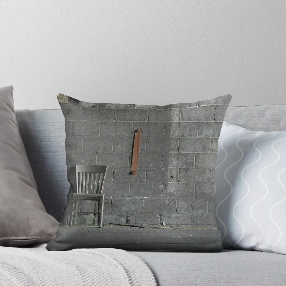 Abandoned wooden grey chair resting against a grey concrete block wall in an abandoned carbide graphite industrial  Throw Pillow