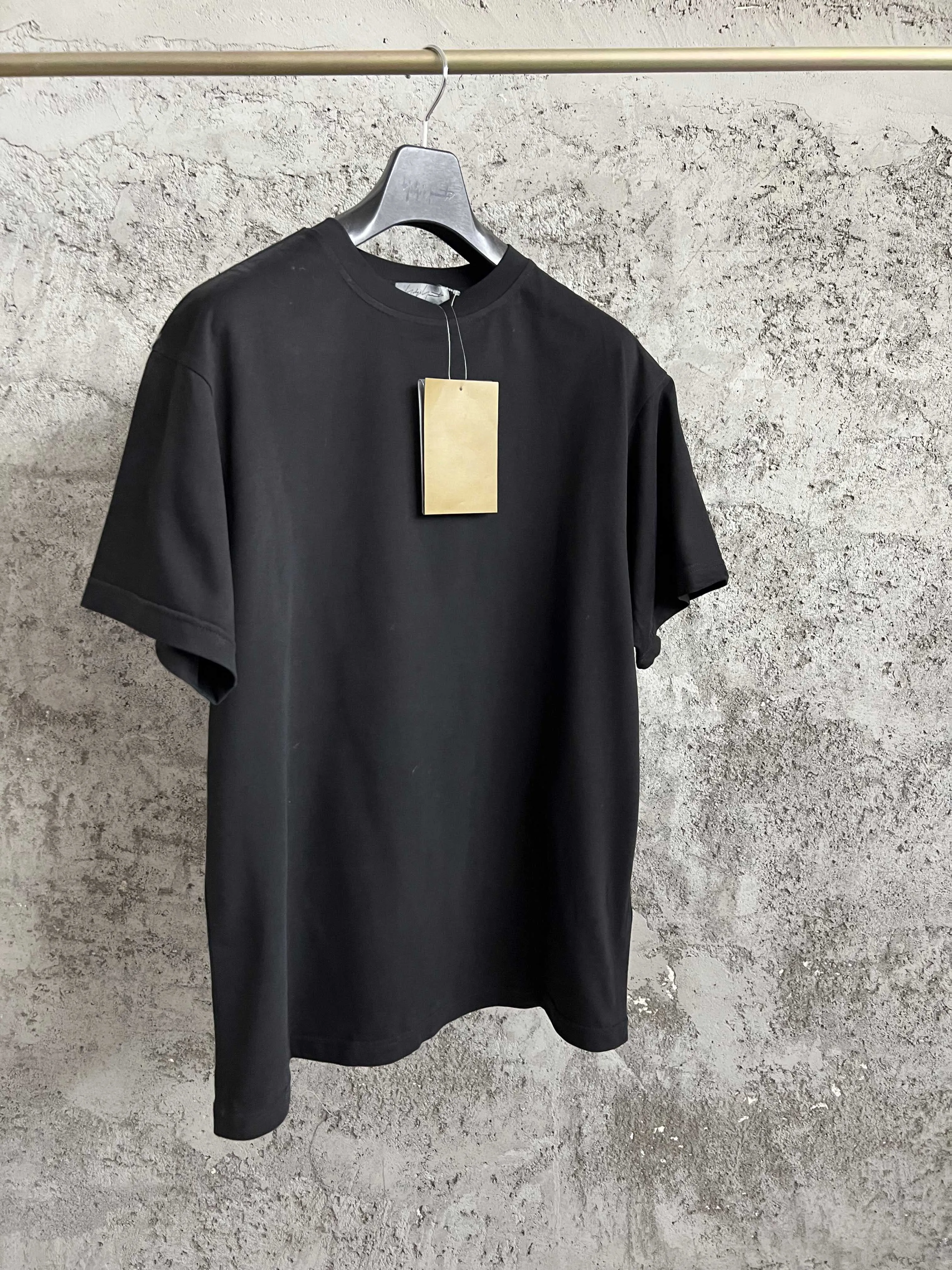 A black T-shirt with a printed round neck and a floral pattern on the back