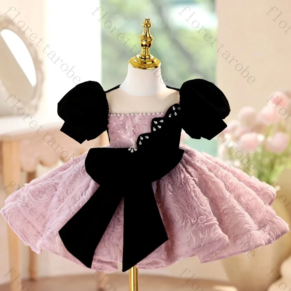 Vestido de Fiesta Personalizado para Niña en Rosa Empolvado, con Mangas Abullonadas de Terciopelo Negro, Lazo Grande con Pedrería y Falda con Textura de Rosas y Volantes, para Bodas