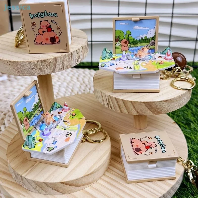 Cute Capybara 3D Pop‑Up Book Keychain, Creative Foldable Mini Story Book Key Ring with Bell, Backpack Bag Charm Pendant Gift
