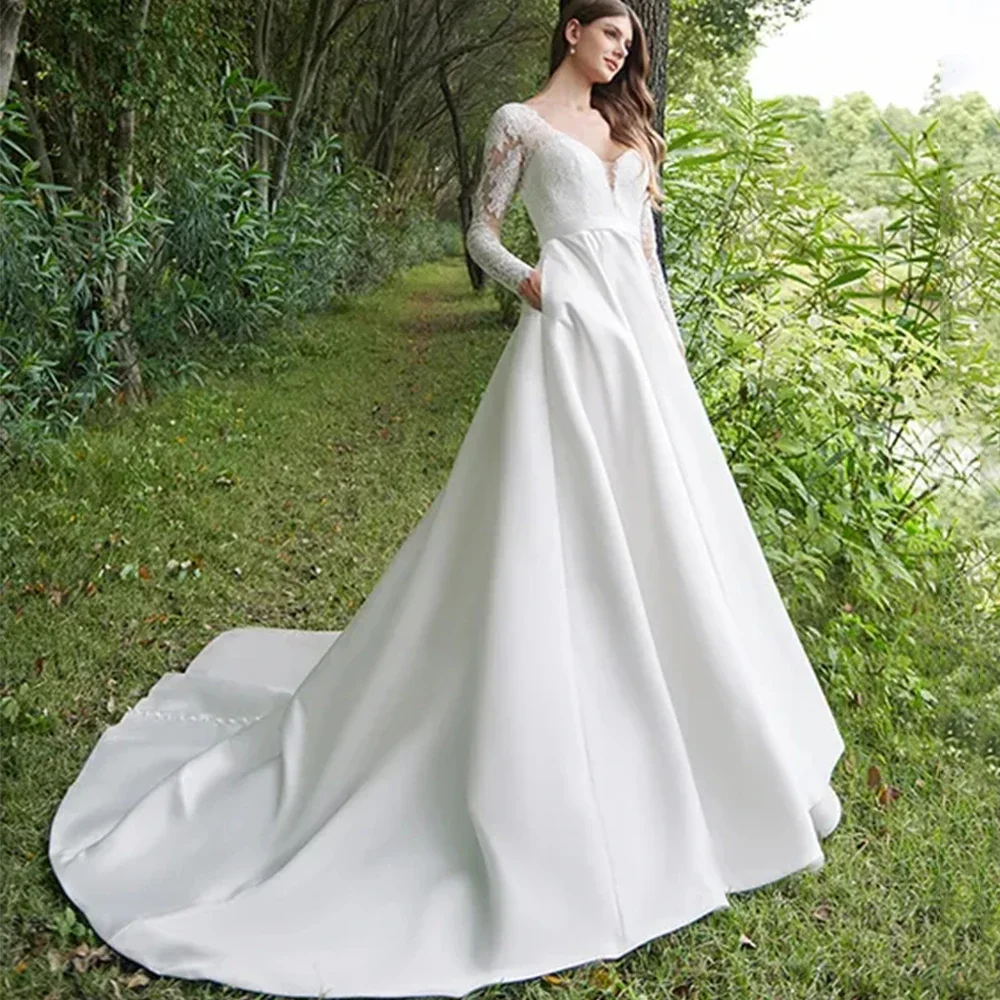 فستان زفاف أنيق بأكمام طويلة من الدانتيل والساتان ورقبة على شكل حرف V بطول الأرض مع أزرار وجيب فساتين زفاف بحزام خلفي مفتوح