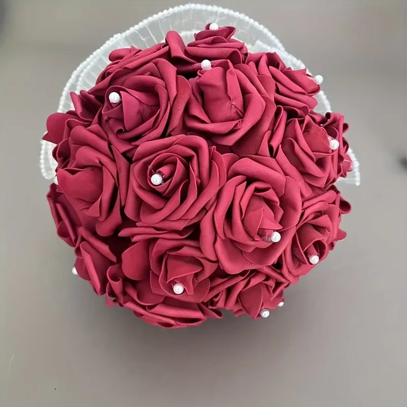 Une robe de mariée ornée de belles perles et captivantes, entourée de bouquets artificiels en forme de rose tenu dans les mains