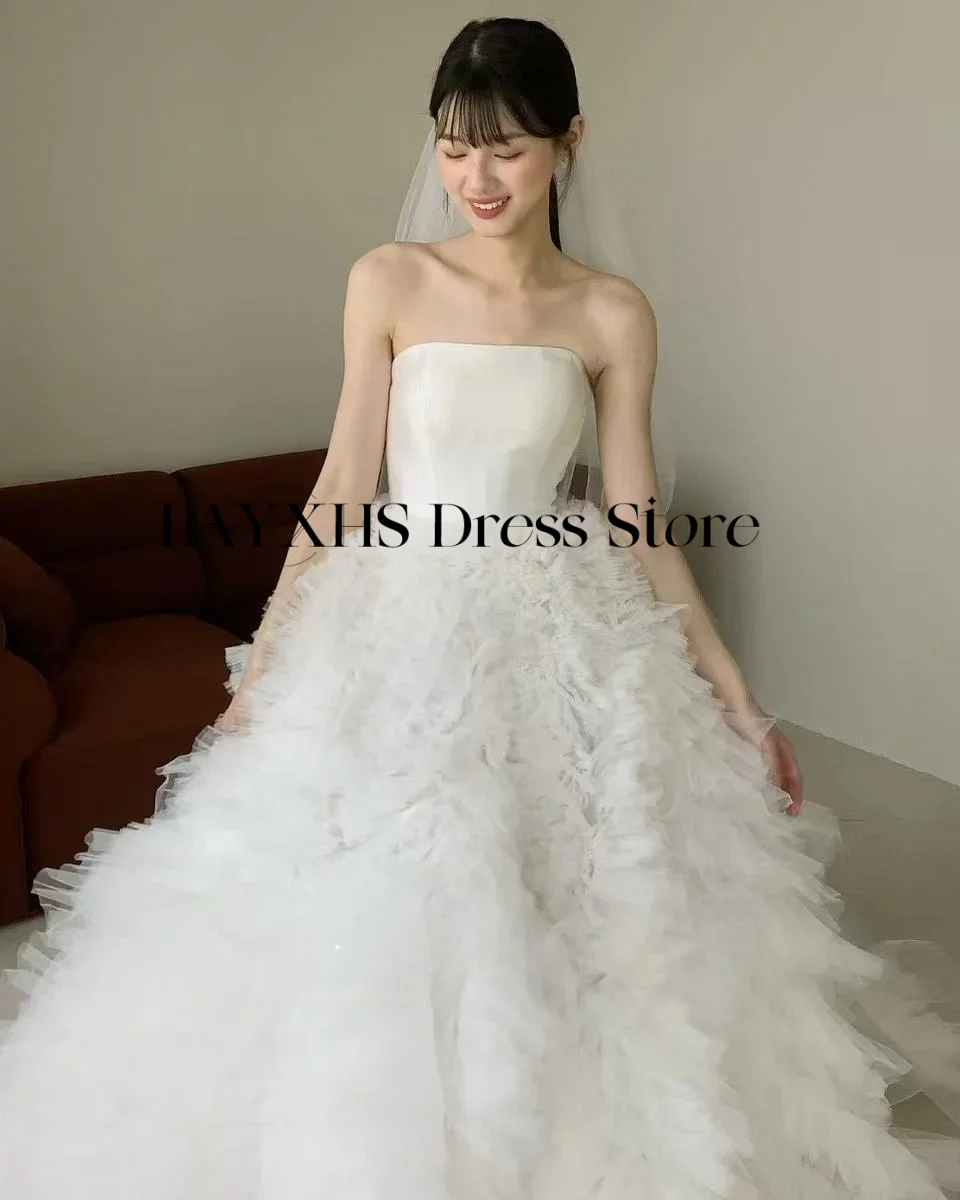 ชุดแต่งงานสีขาวแบบไร้สายหรูหรา ทรงเอไลน์ สไตล์เกาหลี-ญี่ปุ่น ผ้าซาตินและผ้าทูลล์ สำหรับถ่ายภาพ ชุดเจ้าสาวสั่งตัดได้ รุ่นใหม่ล่าสุดปี 2026