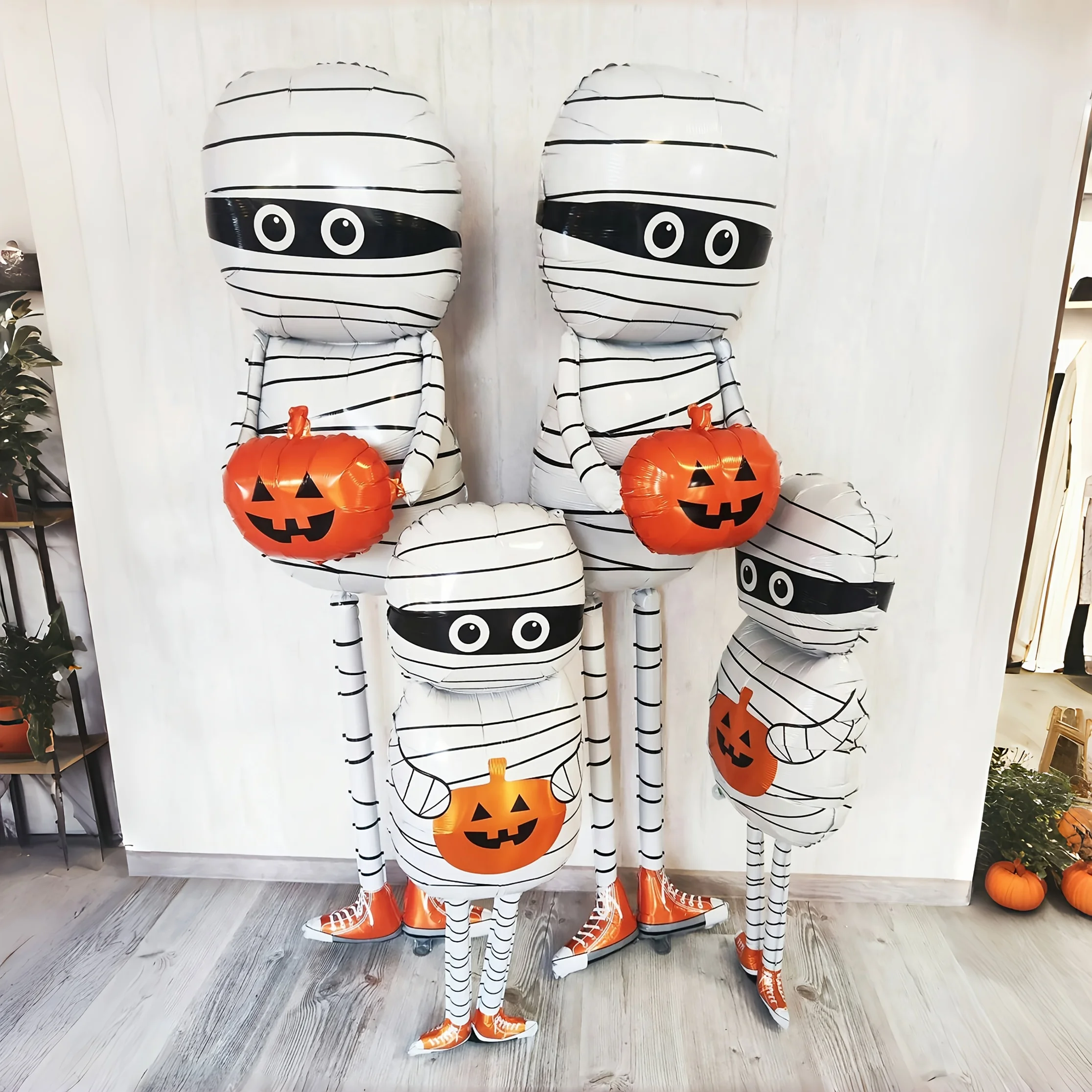 مومياء تحمل بالون من رقائق الألومنيوم اليقطين باللون الأبيض والبرتقالي لعناصر رعب لتزيين حفلات الهالوين