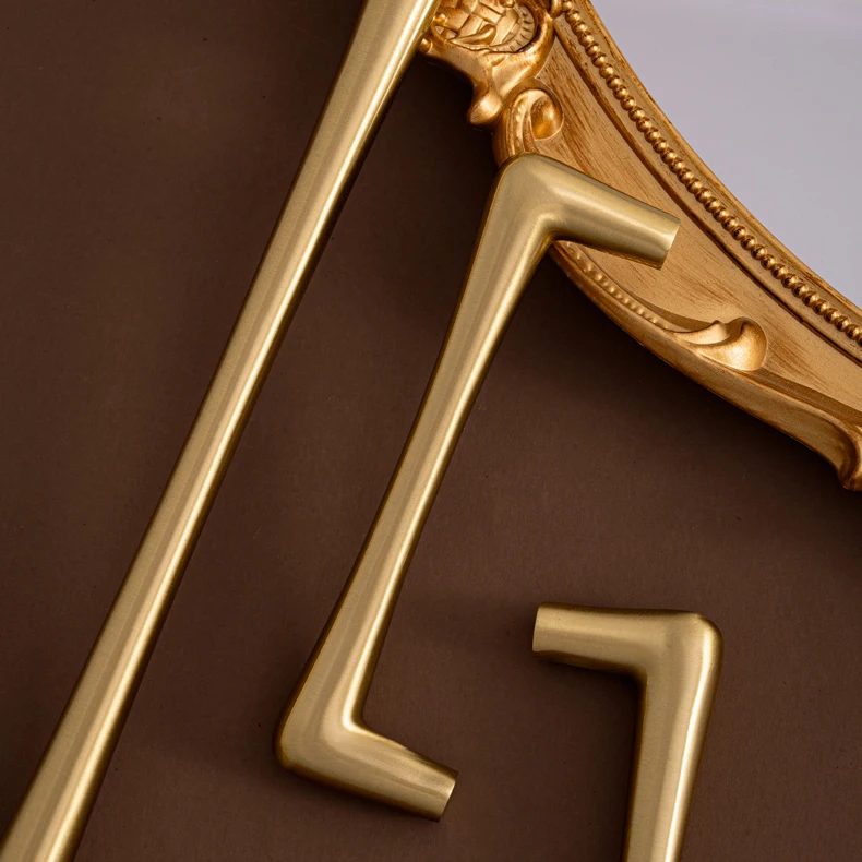 Brass bar handles shown beside an ornate mirror frame