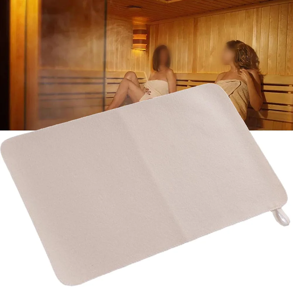 White felt sauna cushion and bath mat on a wooden bench in a spa shower room.