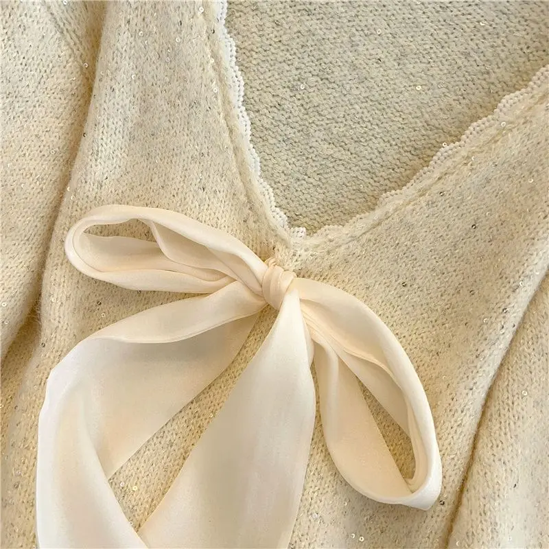 Francuski sweter damski z dużym dekoltem w kształcie litery V i kokardą, elegancki, jesienno-zimowy, średniej długości.