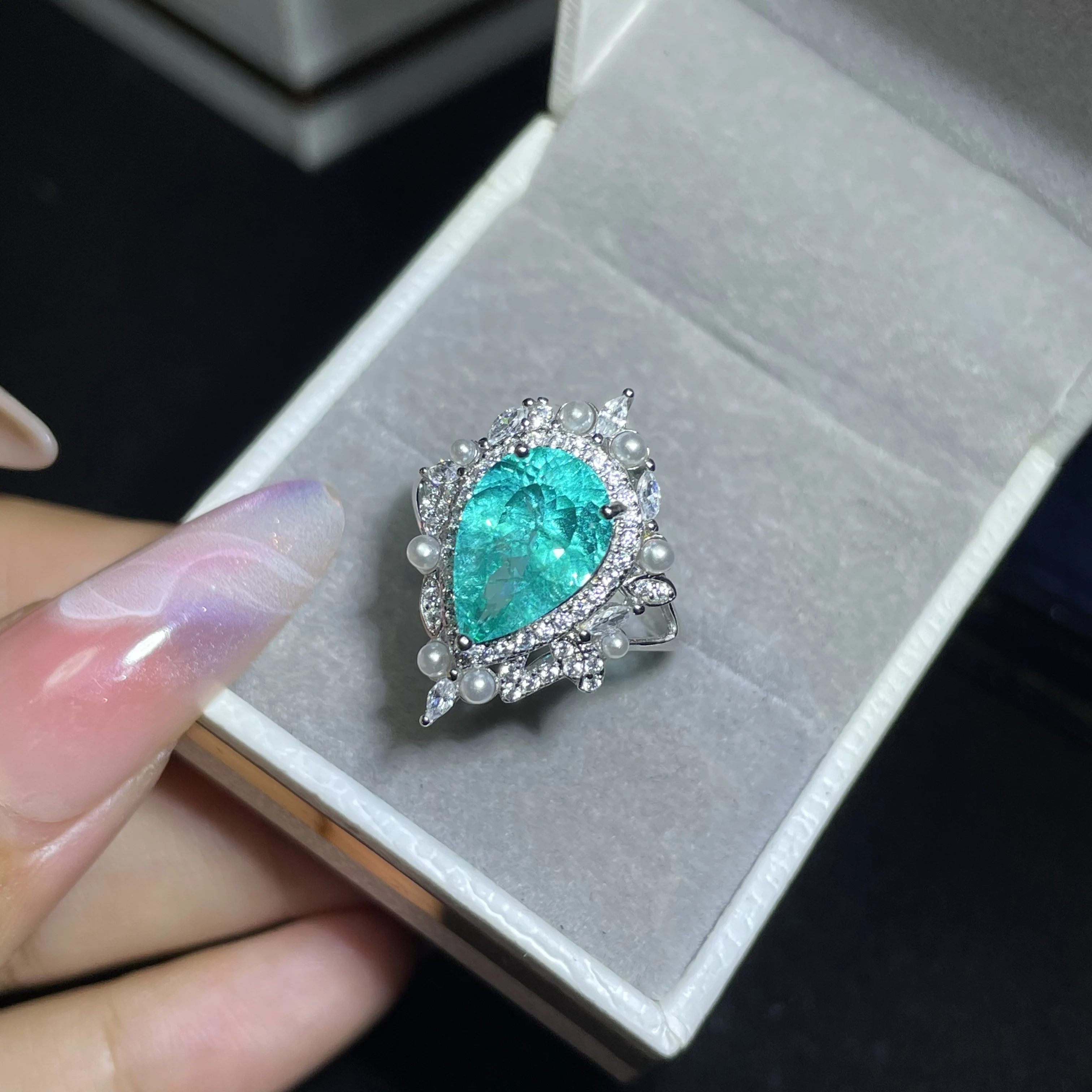 Highly saturated sky blue Paraiba diamond engagement ring in pear shape, with a sophisticated design for women
