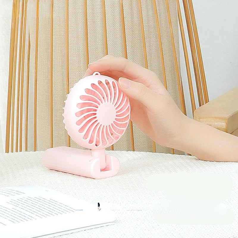 New foldable hand-held small fan Mini portable desktop fan Simple shape, strong wind speed, driven by two AA batteries