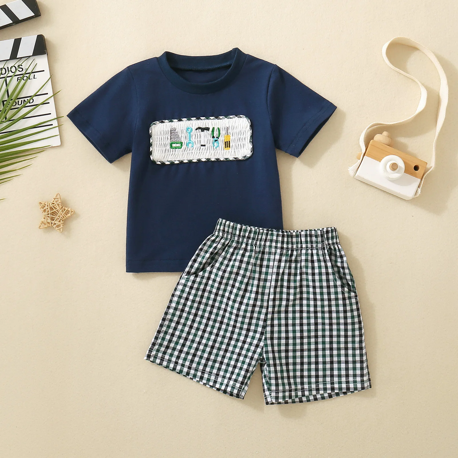 

Детский комплект из двух предметов: футболка с коротким рукавом королевского синего цвета с вышивкой в виде автомобиля и шорты в клетку, унисекс.