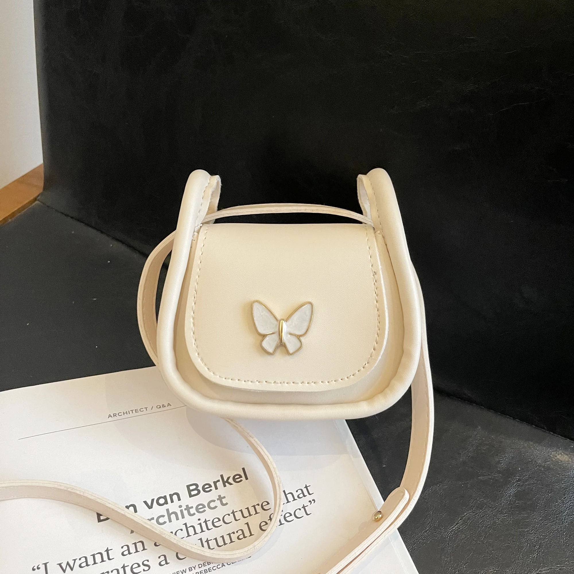 

Simple and stylish beige mini crossbody bag for women, featuring a small butterfly accessory and a PU material flap design.