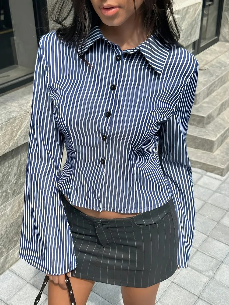 بلوزة نسائية بياقة قميص وأكمام منتفخة قصيرة بخطوط عمودية زرقاء داكنة، تصميم بسيط بأكمام واسعة قليلاً وخصر ضيق