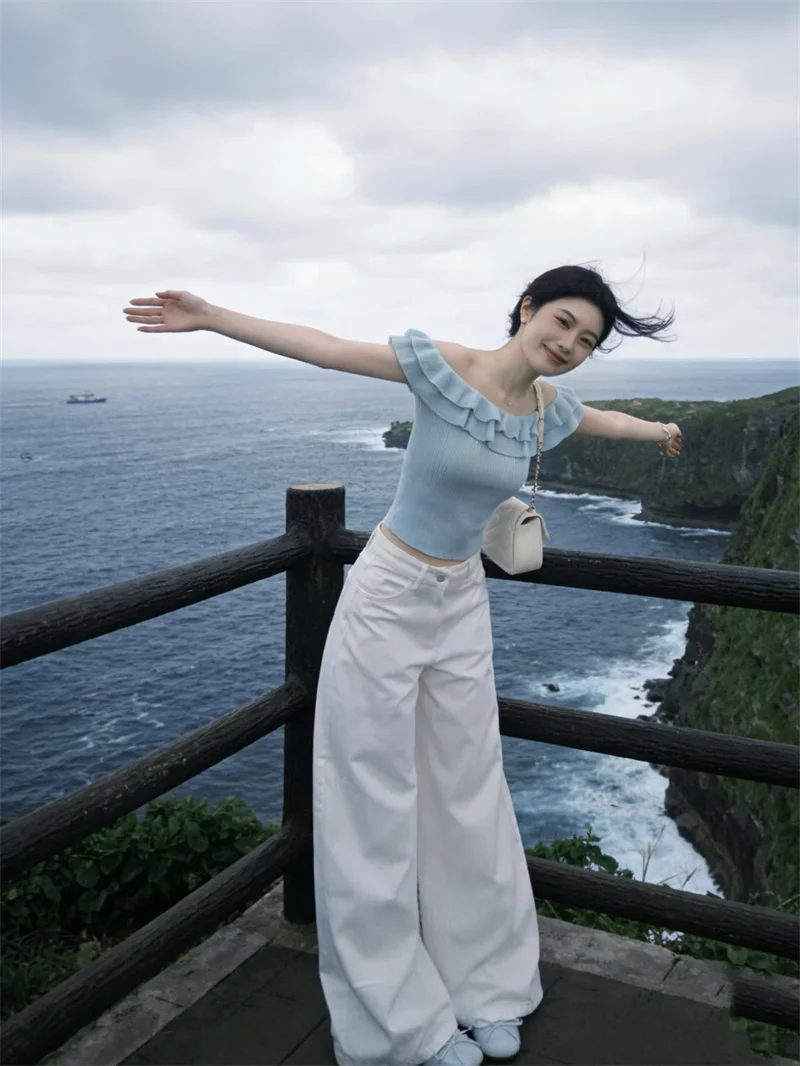 

Синий вязаный комплект из двух предметов: топ на одно плечо с коротким рукавом и свободные брюки. Летний повседневный ансамбль для женщин, омолаживающий образ.