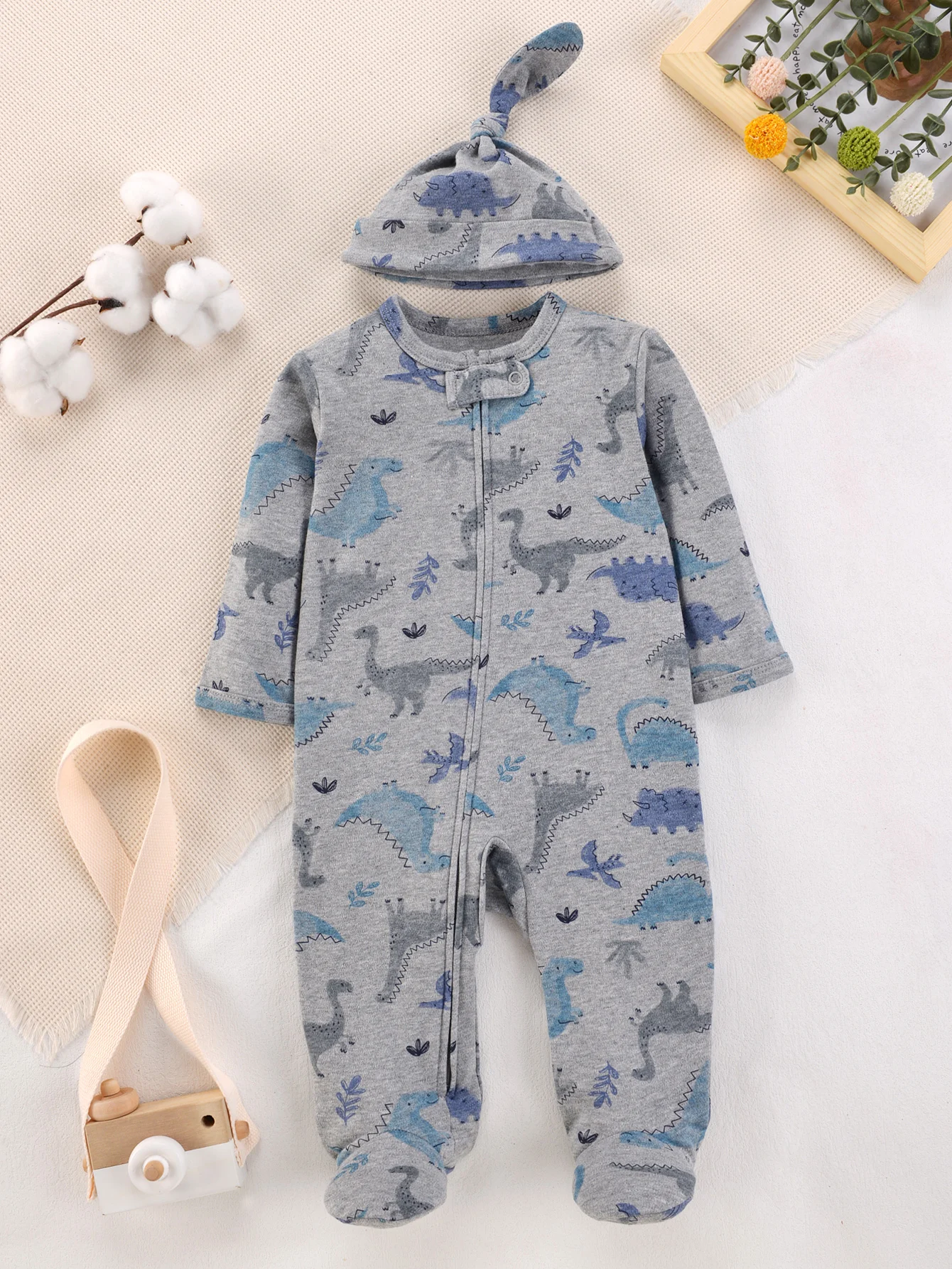 Grauer Baby-Strampler mit blauem Dinosaurier-Print, weicher Baumwoll-Strampler mit Reißverschluss und passender geknoteter Mütze für neugeborene Jungen, ganzjährig tragbar.