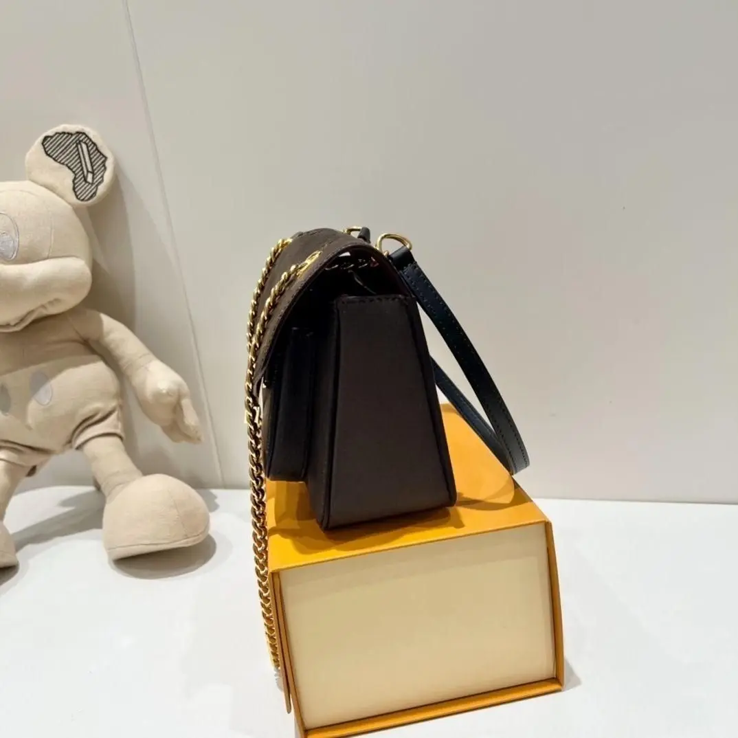 Black pebbled leather flap crossbody bag, herringbone envelope-style front design, chunky metal chain shoulder strap, medium square shape.