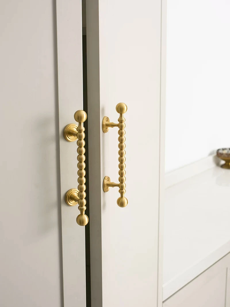 Close view of beaded brass pull next to a white drawer unit