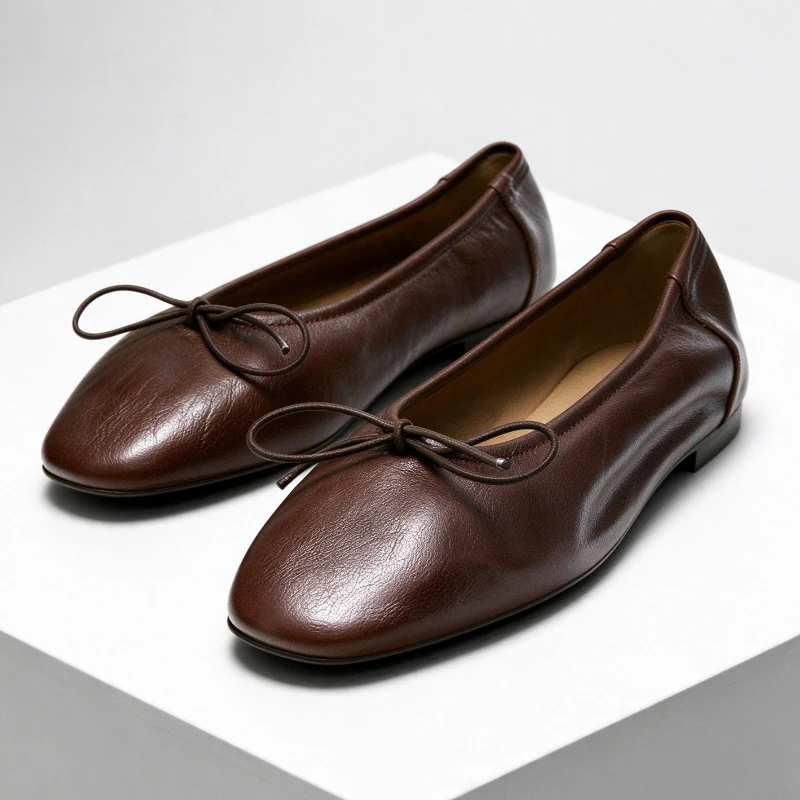 Zapatos de diseño para mujer, tipo bailarinas y mocasines, de cuero suave color marrón, con lazo decorativo, punta redondeada y diseño fruncido, fáciles de poner y quitar, y muy cómodos.