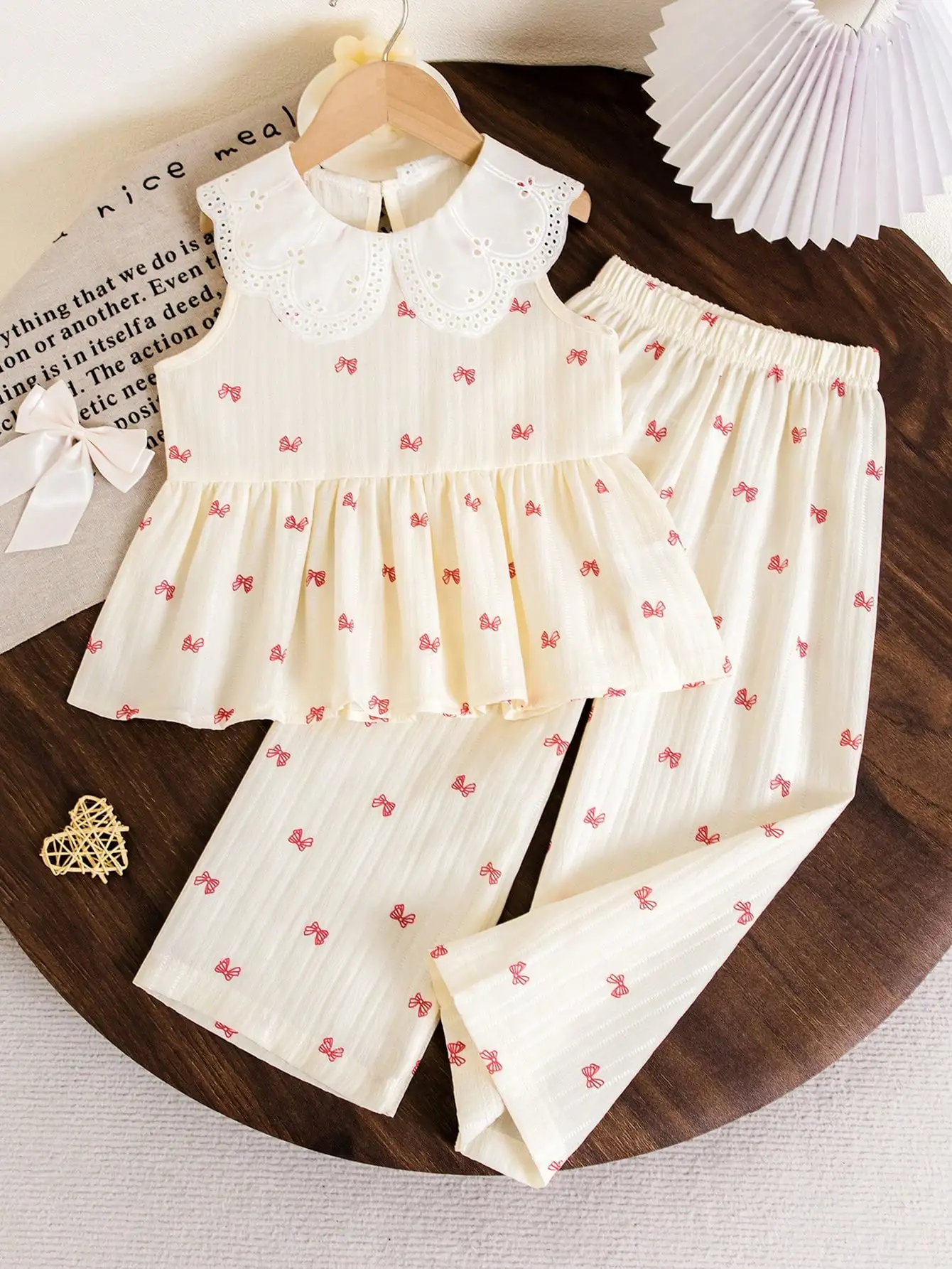 Little Girl's Off-White Bowknot Large Lapel Suit, with Red Bowknot Print on an Off-White Base, Featuring an Exquisite and Cute Large Lapel Design, Sleeveless Top + Long Pants Style, Suitable for Spring and Autumn School Trips, Family Gatherings, and Vacation Photoshoots, Showcasing the Gentle and Sweet Temperament of Little Girls. Spring and Summer.