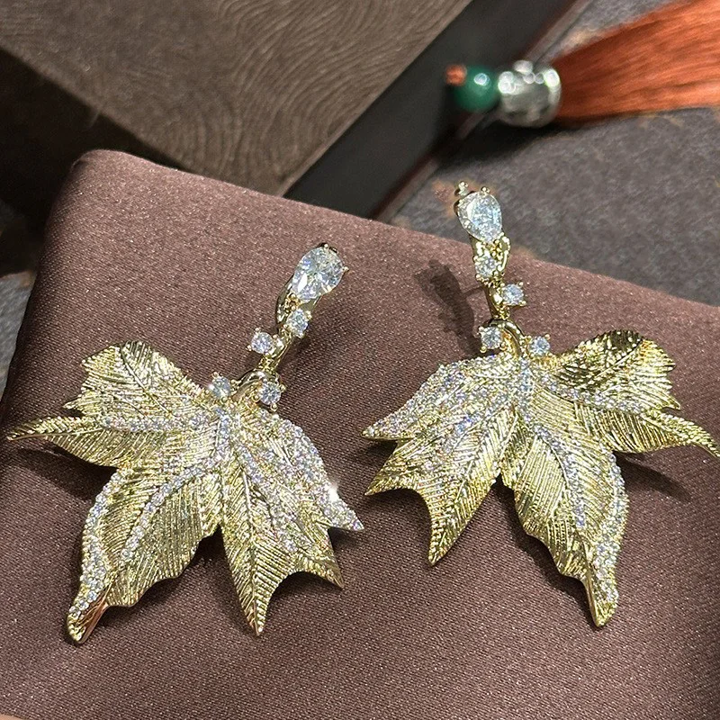 Unique and minimalist earrings with a matte metallic finish, leaf pendant, super shiny and full of diamonds, gold exquisite mapl