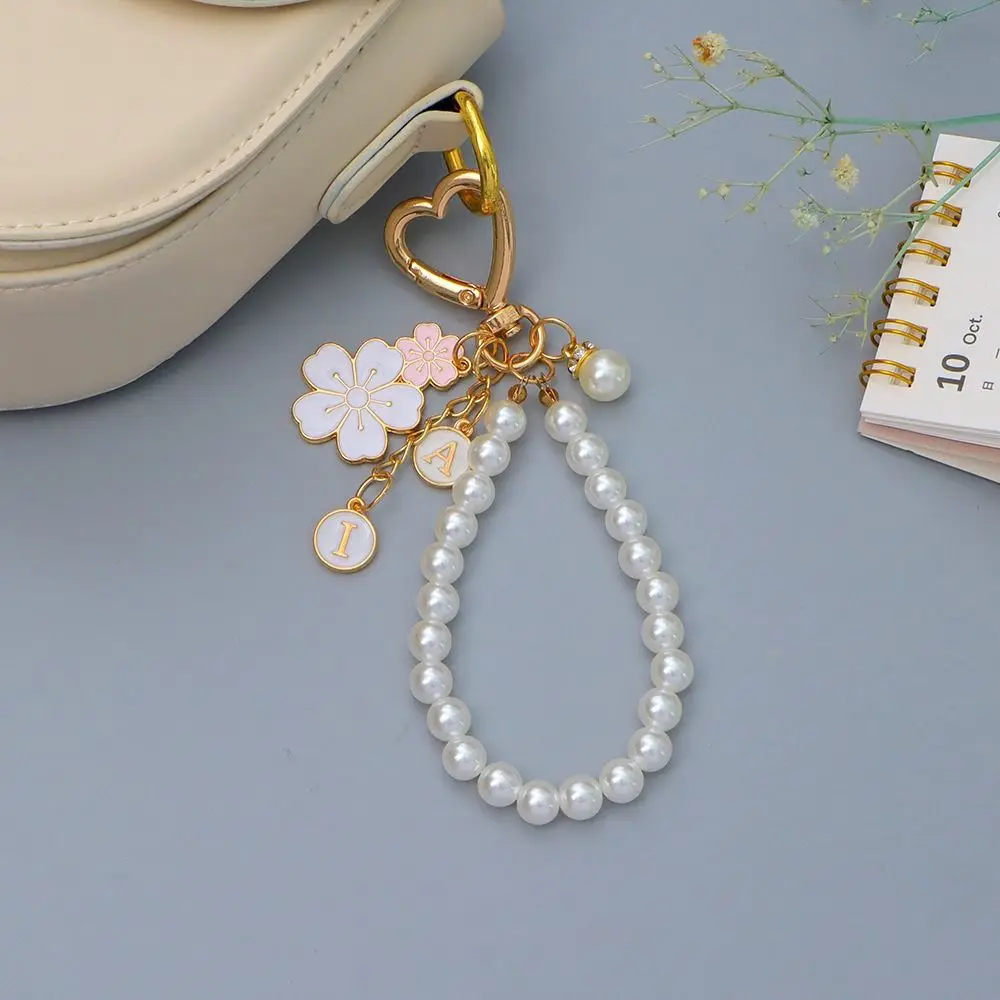 LLavero de flores de cerezo con colgante de letras a la moda, cadena con cuentas de perlas a la moda, funda para auriculares, dijes, accesorios para bolso