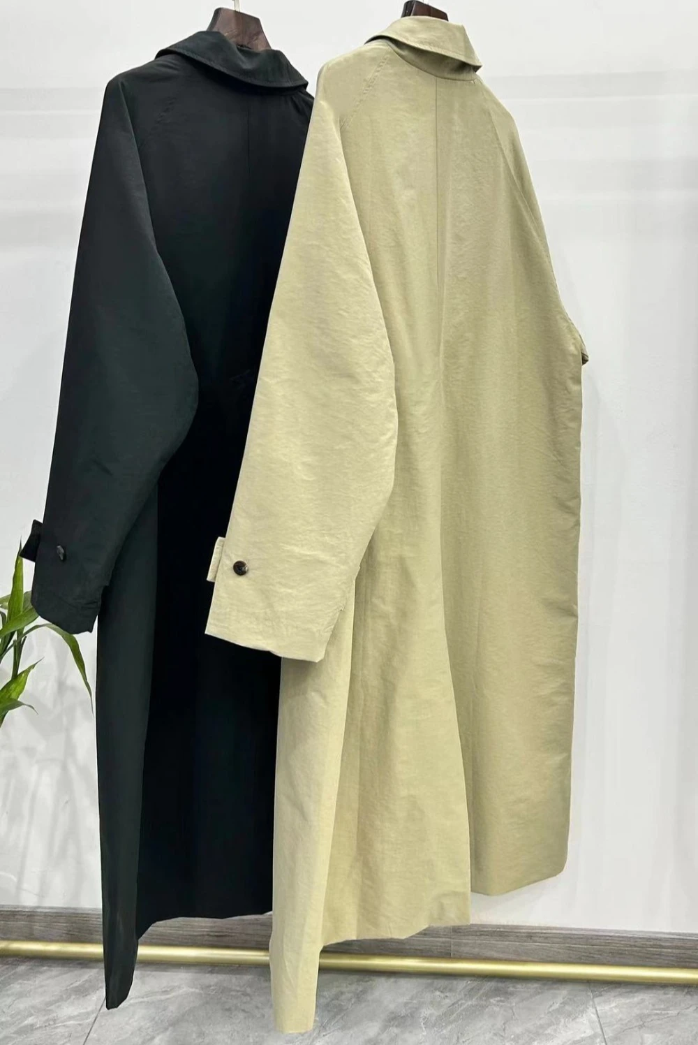 Jesienny płaszcz wiatrówka o klasycznym kroju, z wysokim rozcięciem, wykonany z mieszanki bawełny, o kroju litery A, średniej długości, zapinany na wiele guzików.