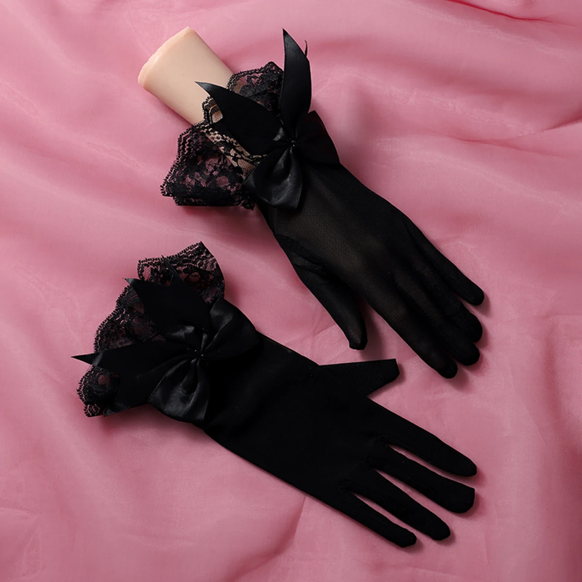 Un par de guantes negros con decoraciones de lazo, adecuados como accesorios para bodas de novia o bailes de mujer