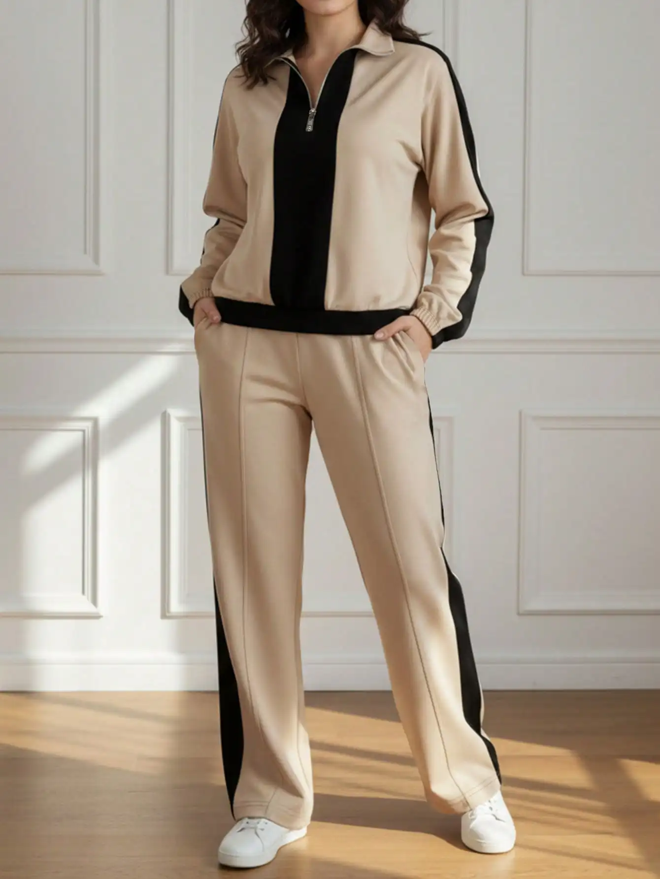 

Женский спортивный костюм бежевого и черного цветов с контрастными полосками, состоящий из топа на молнии до середины груди и брюк с широкими штанинами