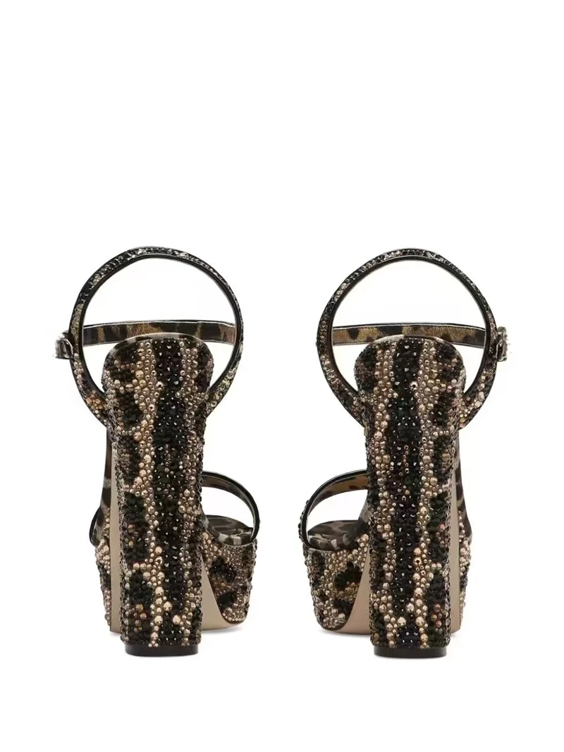 Seksowne platformy na masywnym obcasie typu chunky z paskiem wokół kostki, zapinane na klamrę, z odkrytymi palcami, w wyrazistym wzorze panterki, eleganckie na wieczorne wyjścia.