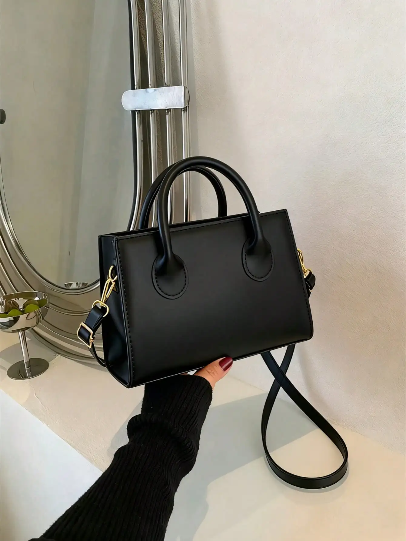 

Минималистичная черная сумка с верхней ручкой и золотистой фурнитурой, из веганской кожи