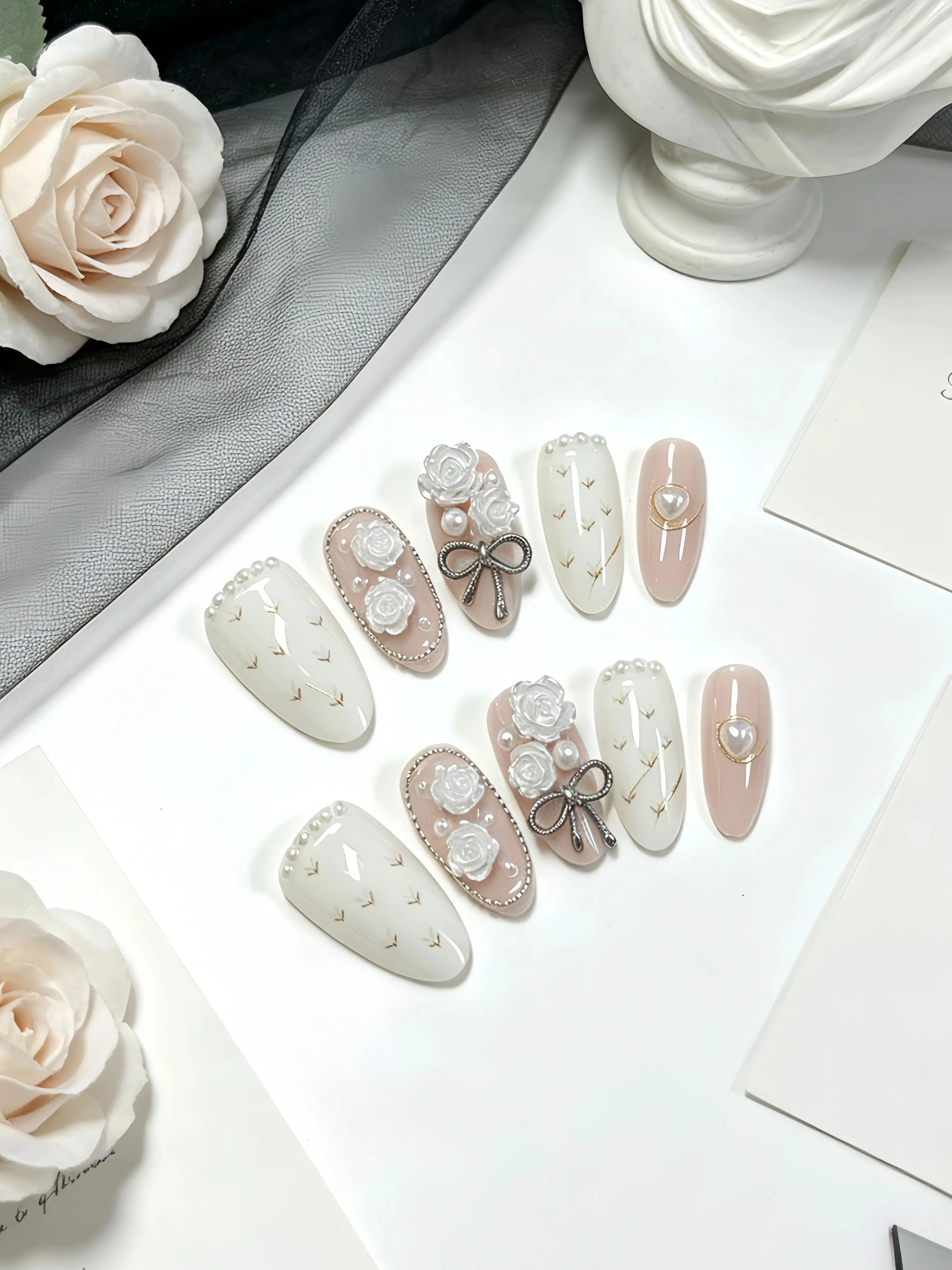 10 faux ongles en forme d'amande, aux couleurs principales abricot nude et rose clair, décorés de chaînes de perles argentées gaufrées camélia et de perles argentées en forme de cœur et de nœuds, dans un style pastoral français. Faux ongles de style coréen et Instagram pour étudiants, jeunes filles et employés de bureau. Convient pour la vie universitaire, les tenues de demoiselle d'honneur, les rendez-vous, les parcs d'attractions, le thé de l'après-midi et d'autres occasions. Comprend une colle gelée et une lime à ongles