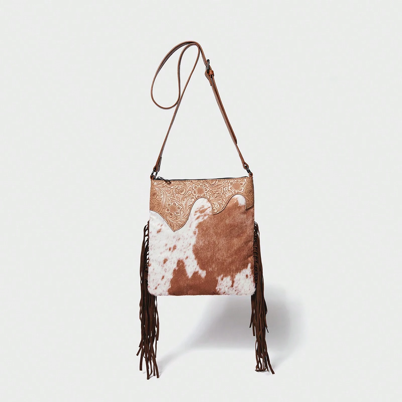 

A crossbody bag with cow pattern, featuring a tassel design and a detachable shoulder strap.