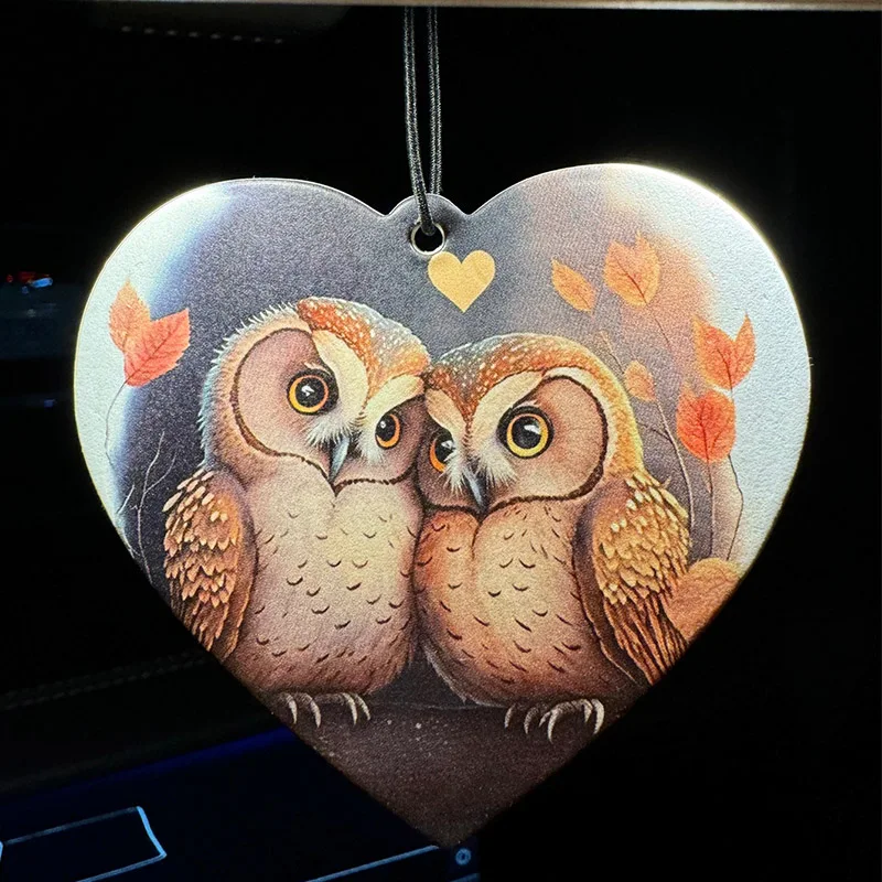 Two owls fly in pairs on a leafy branch of a tree. The couple have a lovely car fragrance