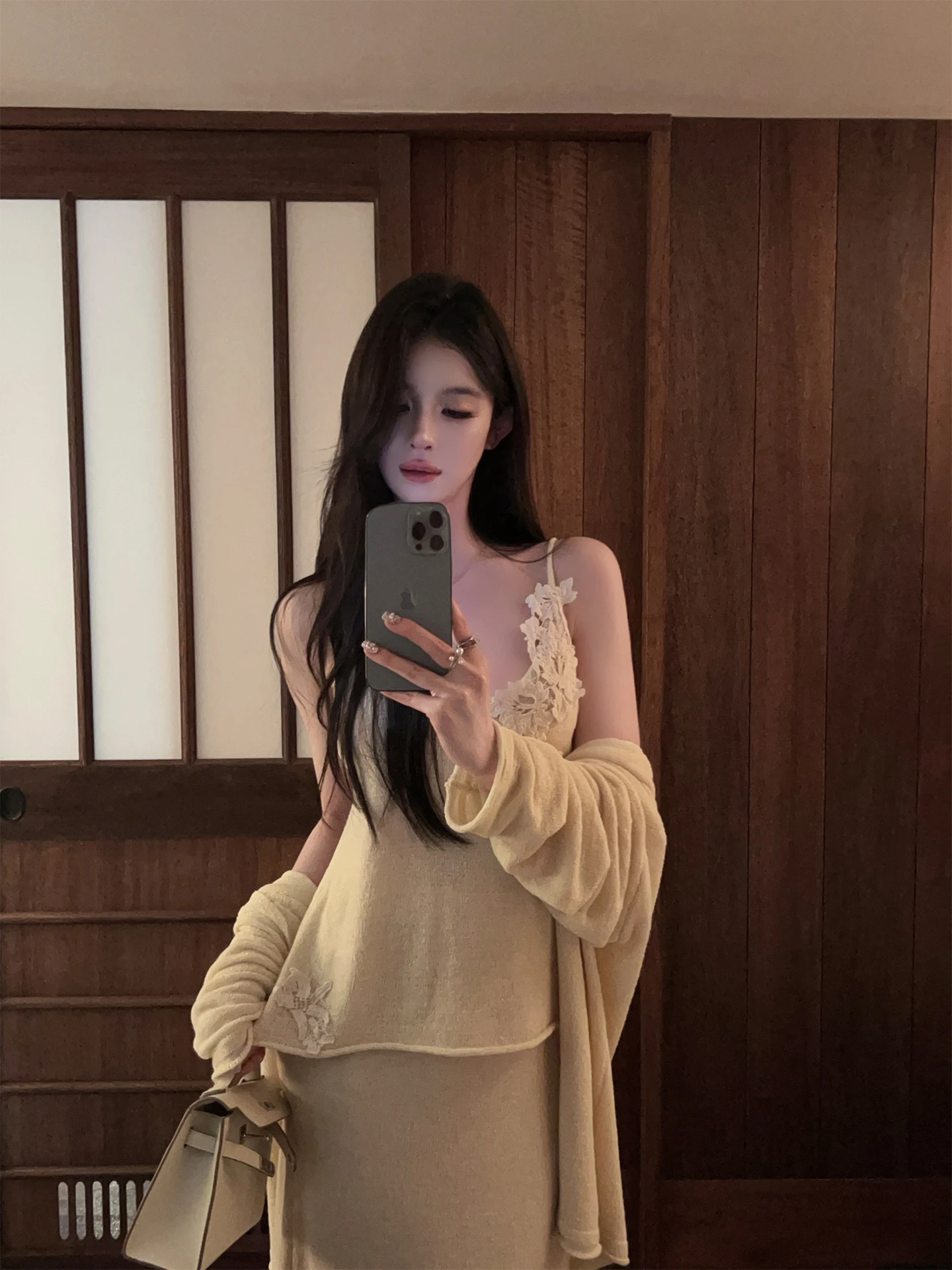 

Комплект из двух предметов: белый вязаный кардиган и топ на бретельках с кружевом, юбка с высокой талией. Модный осенний комплект.