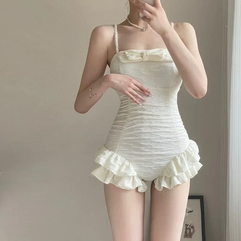 

Элегантный белый слитный купальник с жемчужными бретелями, бантом, рюшами и драпировкой – скромный купальник для пляжа, бассейна и отпуска