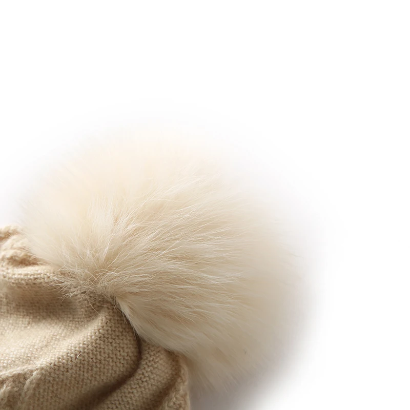 قبعة كرة شعر عصرية للسيدات شتوية سميكة 100% من الكشمير الخالص محبوكة بلون سادة قبعة حماية للأذن دافئة ومقاومة للرياح