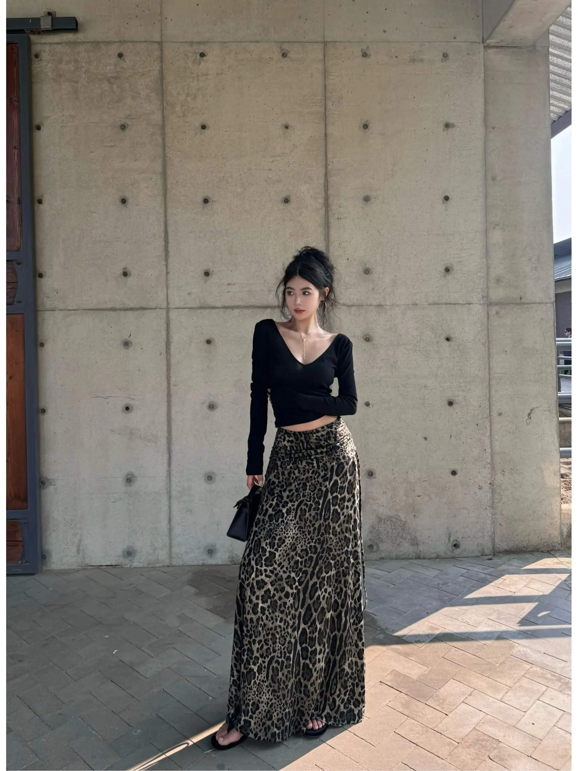 

Элегантный черный комплект из футболки с V-образным вырезом и открытой спиной, с длинными рукавами, и юбки-рыбки с леопардовым принтом. Модный женский весенний наряд из двух предметов.