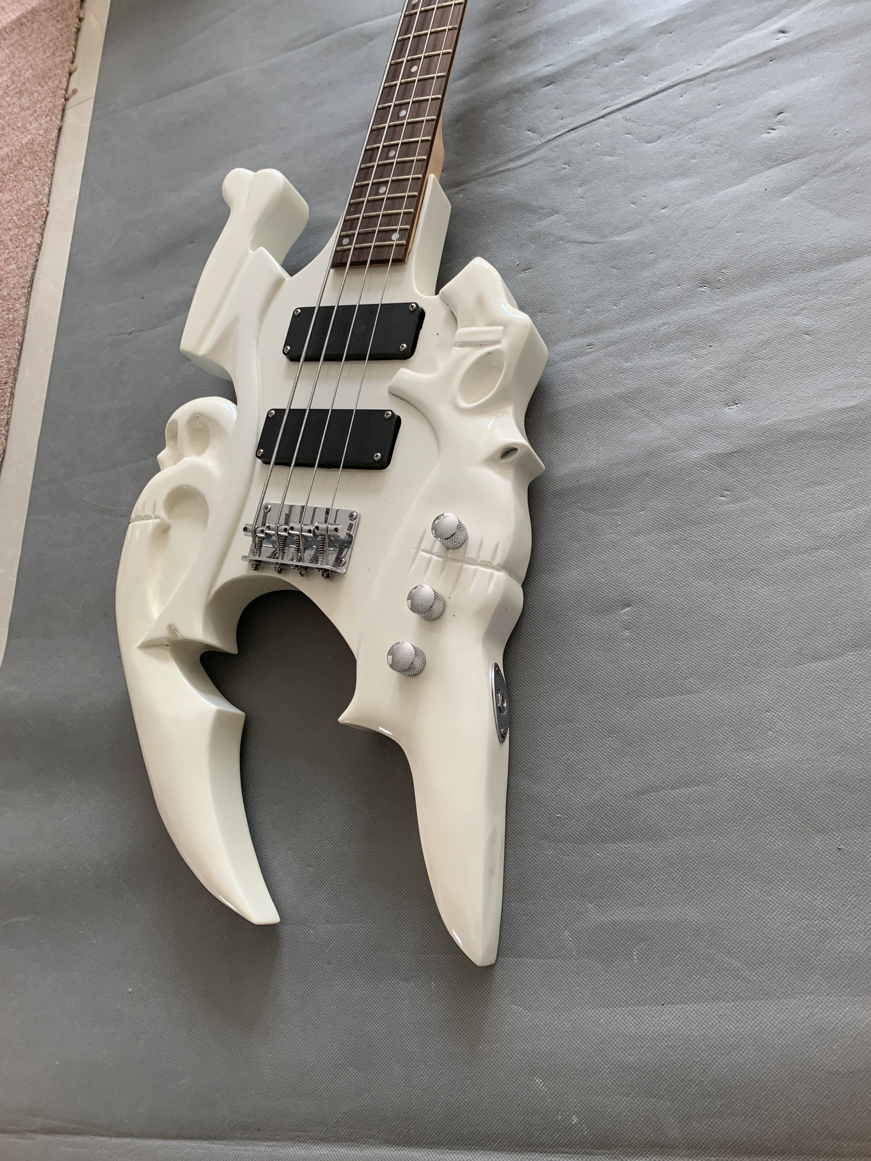 Custom carved skull 4 string electric bass, white body, chrome-plated metal parts, can be customized according to customer requi