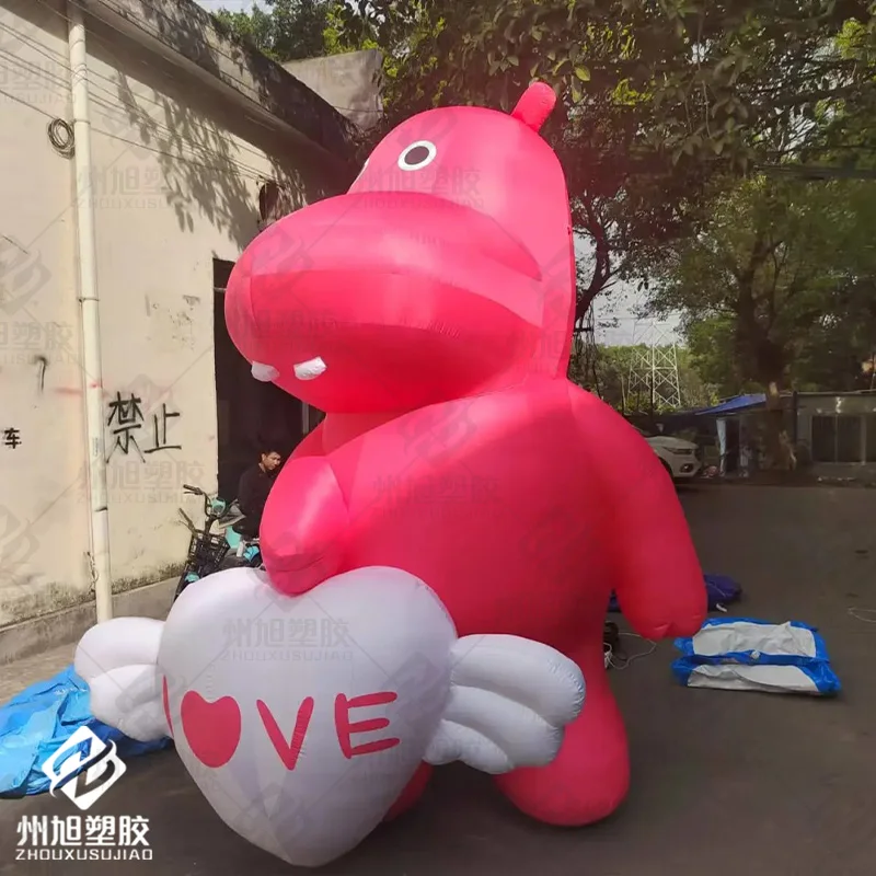 Cartoon inflatable hippo holding white heart with horned wings air model pink animal mascot event mall advertising decoration