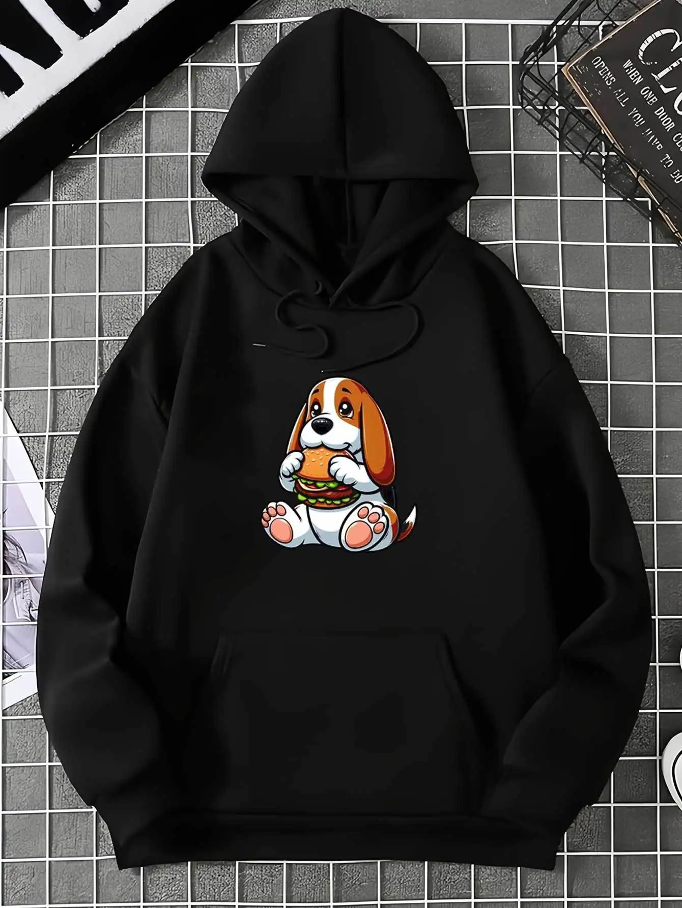 Super Cute Cartoon Puppy Enjoying a Delicious Fresh Burger on a Black Essential Hoodie. This Men's Hoodie Features a Kangaroo Pocket and Drawstring Hood, Perfect for Casual Outings, Music Events, and Festivals.