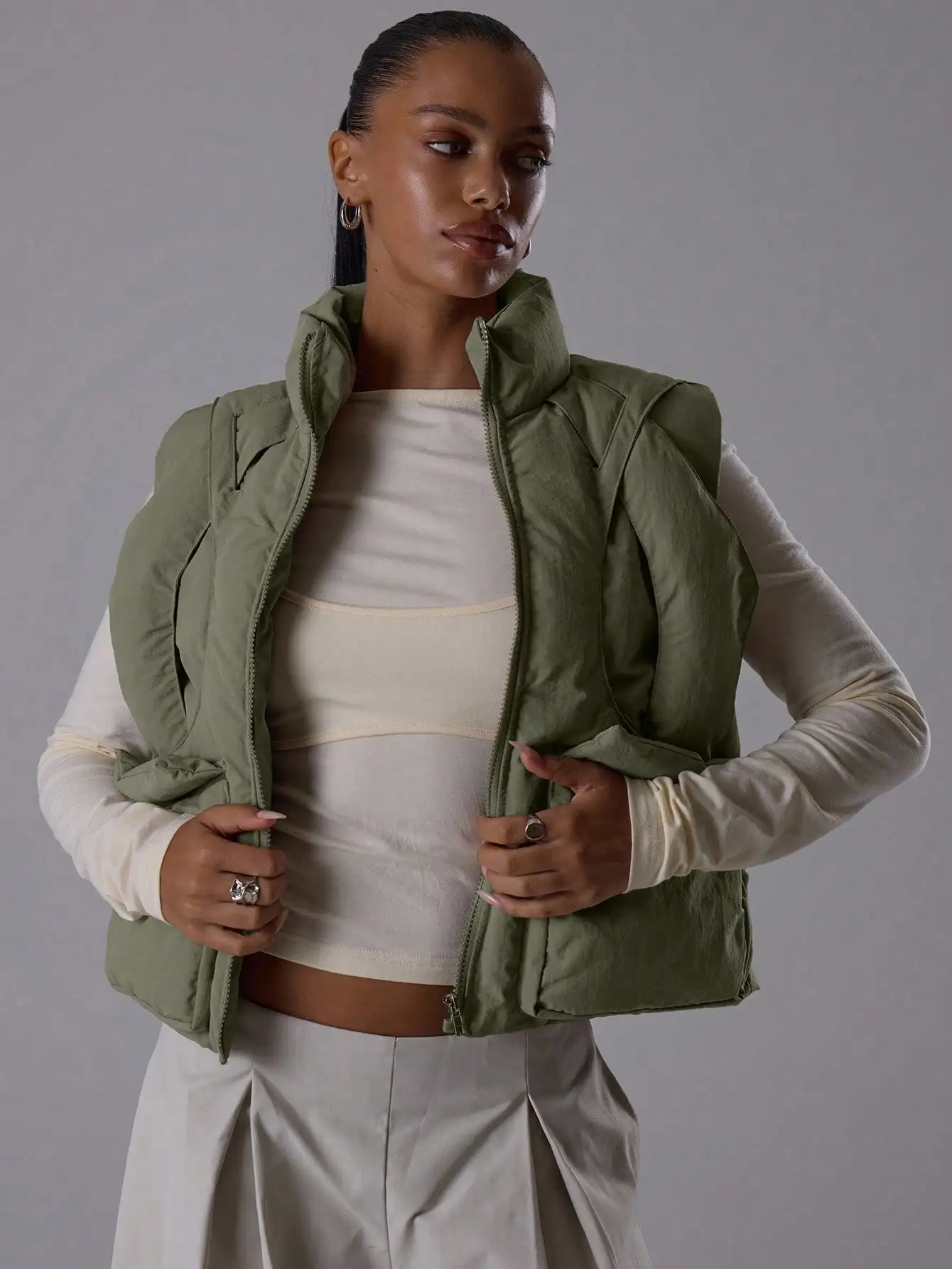 

Оливково-зеленый безрукавный пуховик с высоким воротником и молнией - уличная одежда для осени и зимы