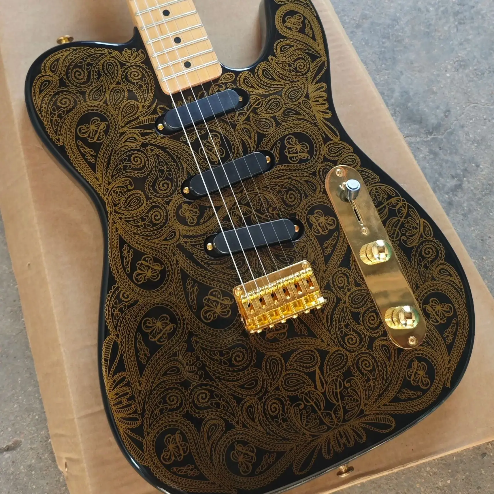 Black six-string electric guitar, gold printed basswood body, maple neck and maple fingerboard with gold hardware.