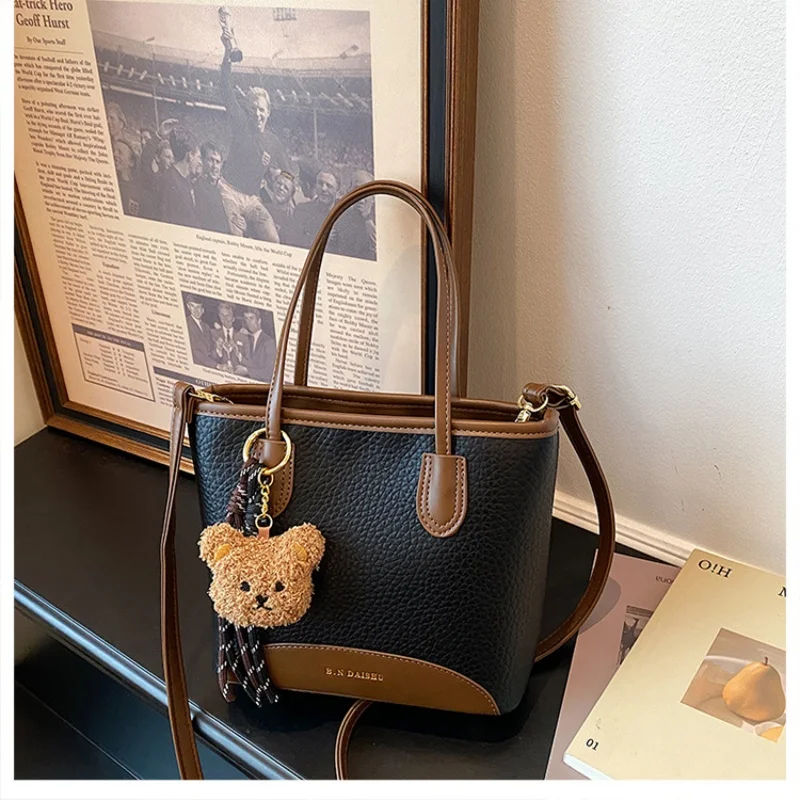 Two-tone pebbled mini tote bag with fluffy bear charm, short top handles & detachable crossbody strap for daily use