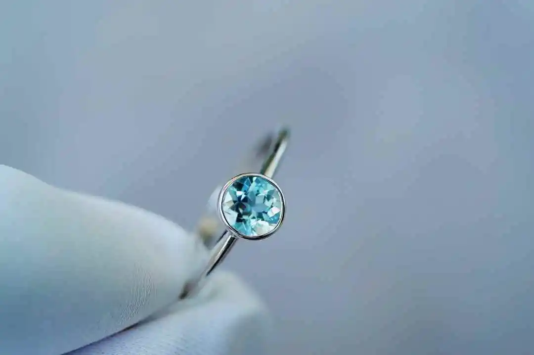 

0.5 carat round brilliant-cut aquamarine, flawless and crystal clear. Set in an 18-carat gold mount, adorned with diamonds. Ice-