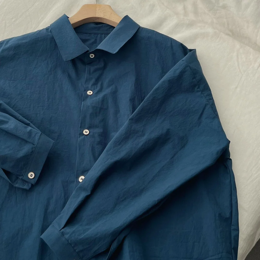 Luźna damska koszula bawełniana w kolorze niebieskim, wysoka ilość włókien, wyprana, w stylu lazy, długi rękaw, kołnierzyk, regularny krój, jednolity kolor.