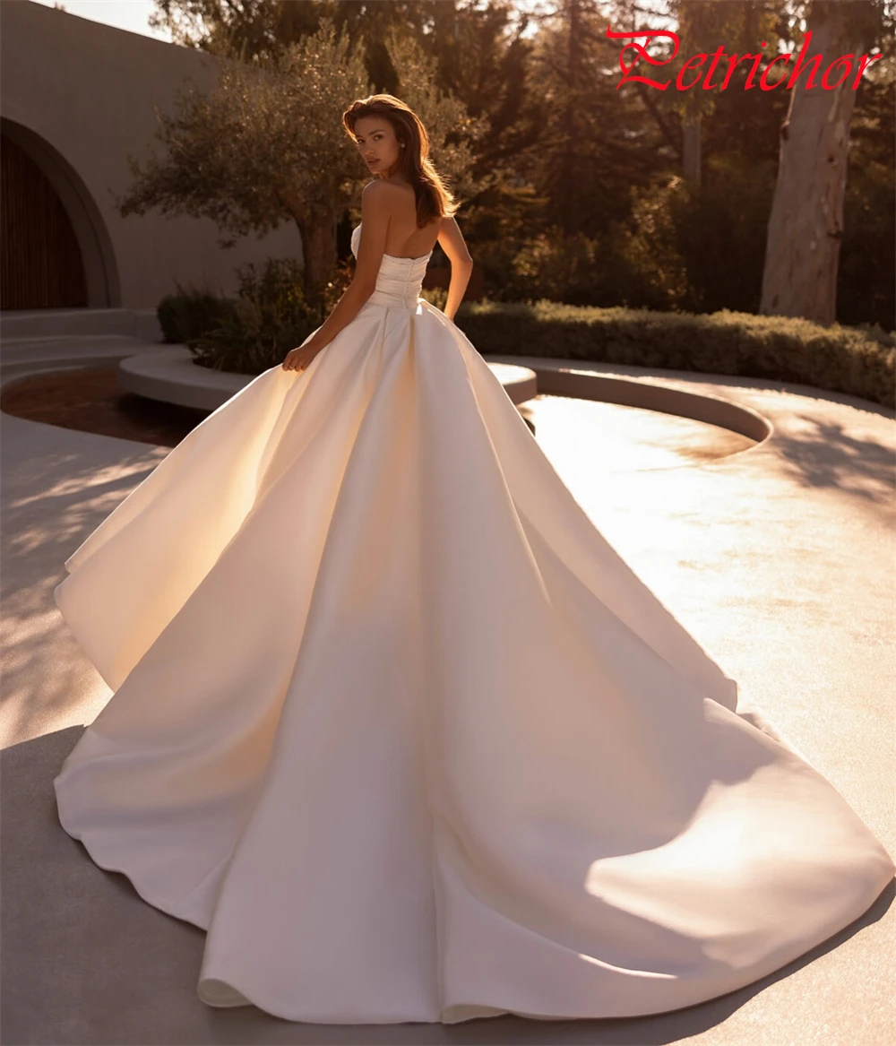 فستان زفاف أنيق من الساتان الأبيض مخصص رسمي على شكل قلب بدون أكمام زي العرائس بوهو على شكل حرف a ذيل شابيل فيستدو دي نوفيا