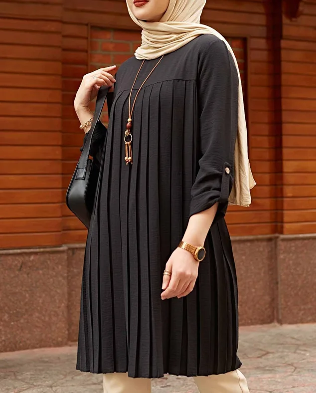 Black pleated tunic showing the front pleats and rolled button-tab sleeve