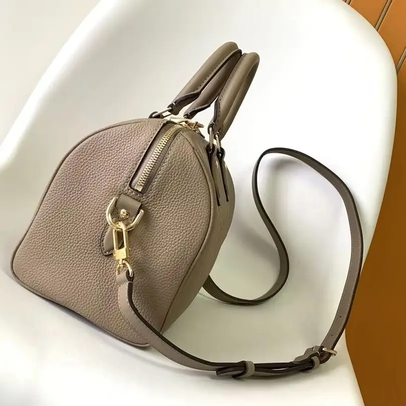 Sac Boston mini en cuir grainé taupe, avec doubles poignées supérieures, bandoulière amovible et breloque clé à fermoir doré.